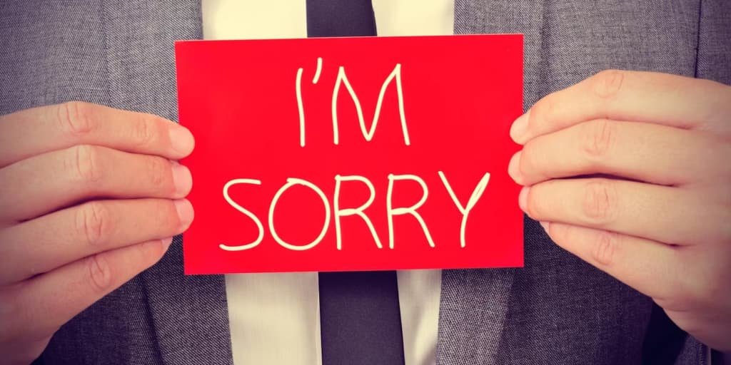 A man holds up an inscription Pardon me on red paper