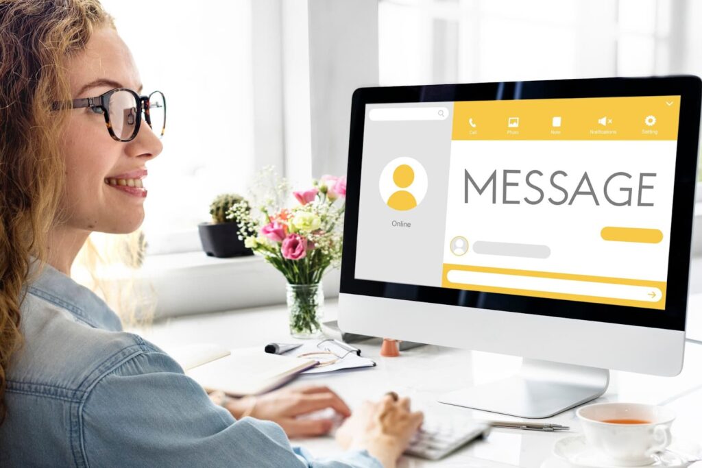 A girl sits in front of a computer and sends a message